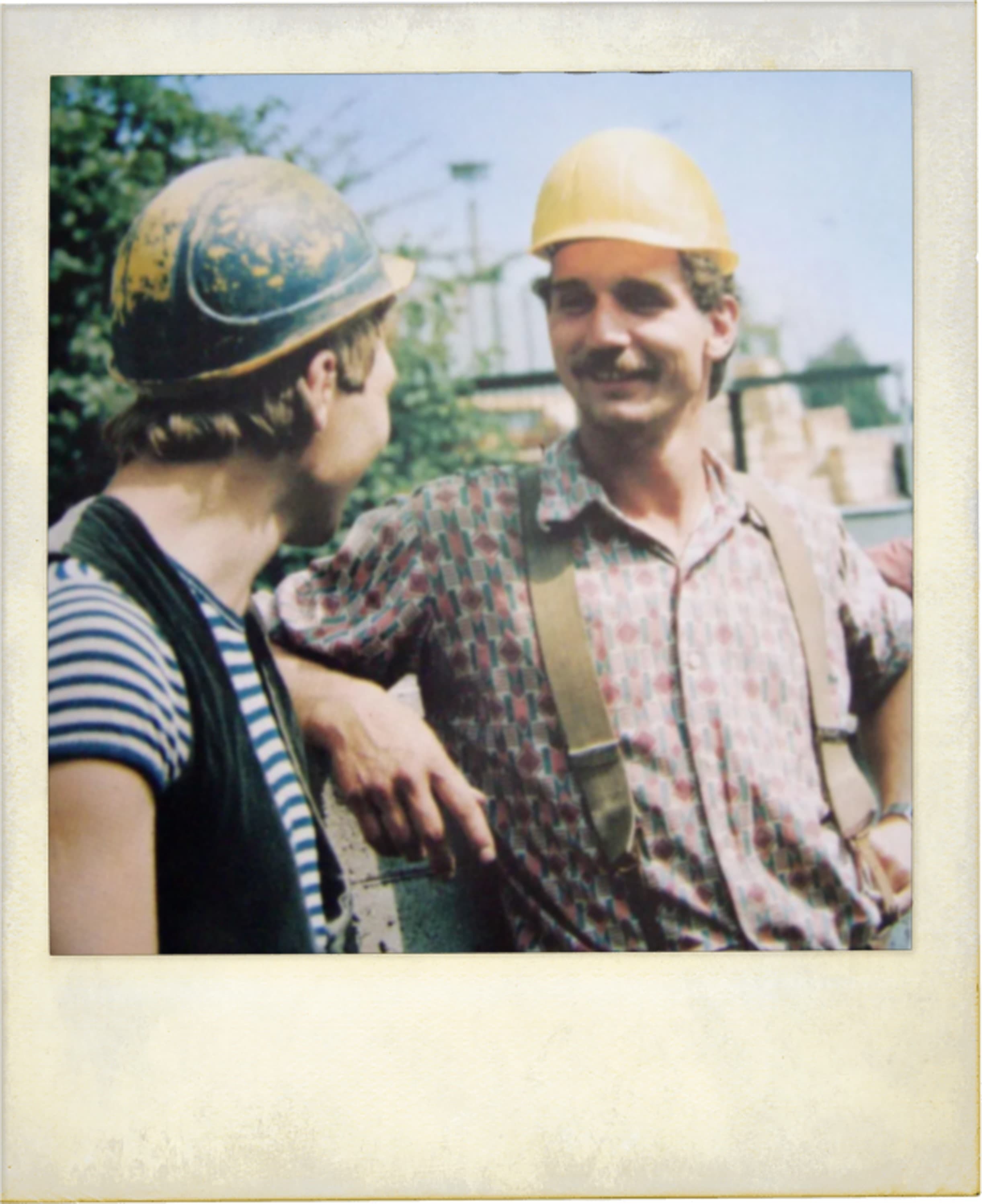 Two linemen in hard hats talking on the job