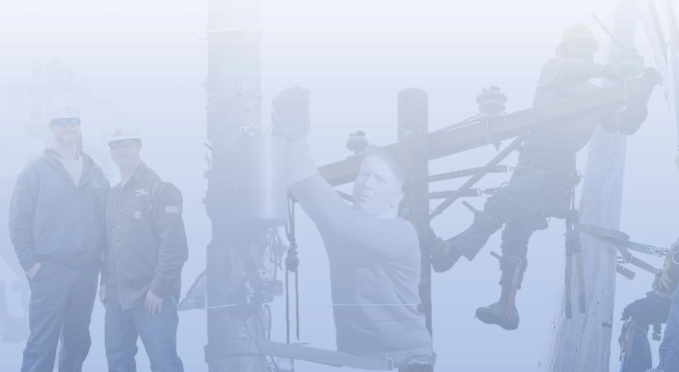 Lineworkers on poles against an overcast sky