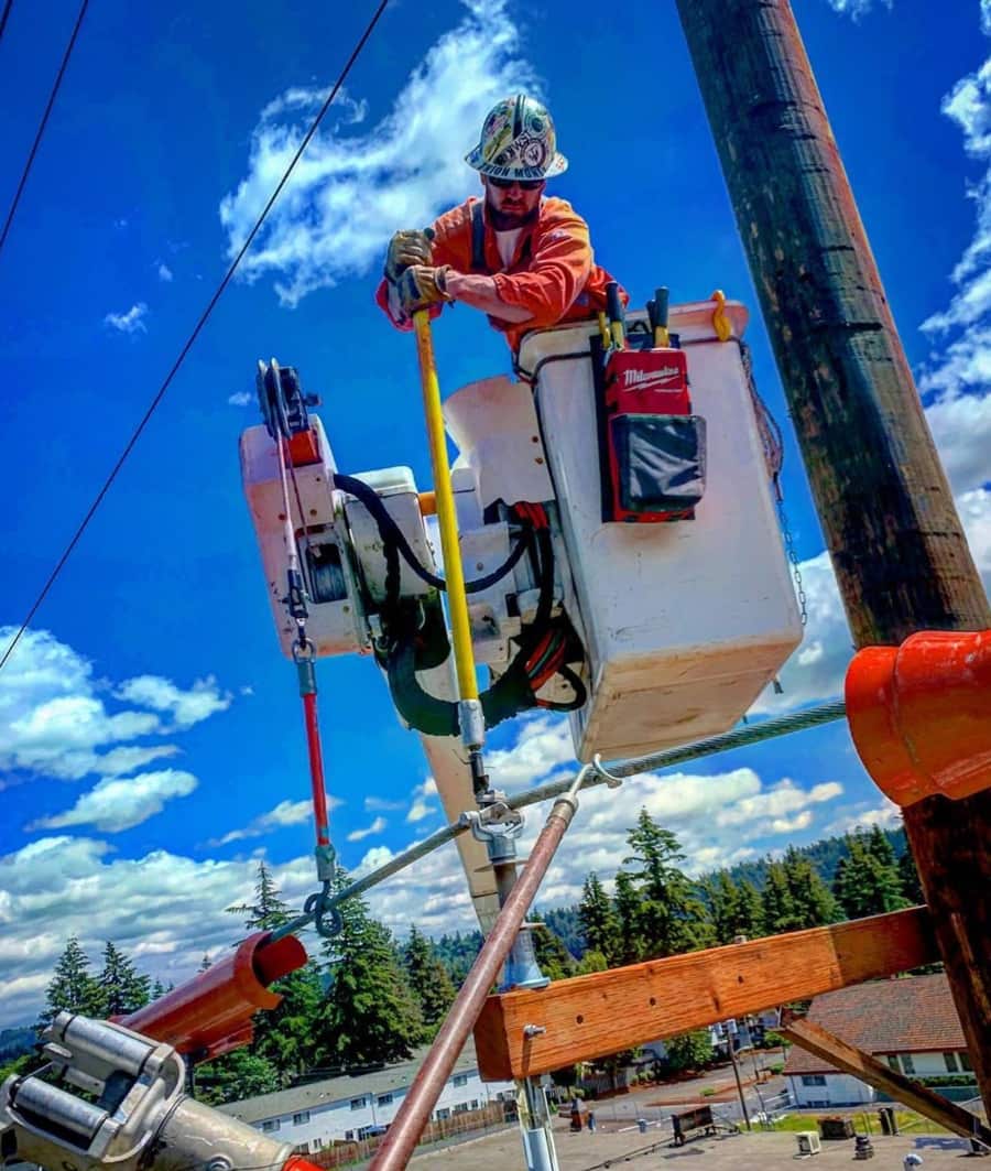 Lineman working from a bucket against a blue sky