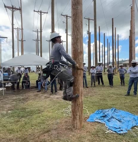 Trainee climbing on hooks in a yard while others watch