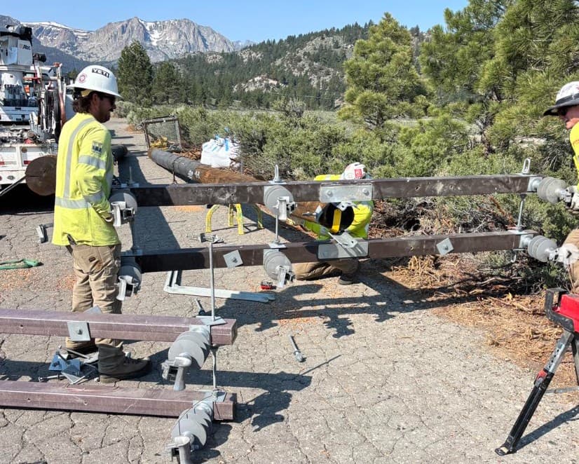 Crew staging a crossarm assembly with mountains behind them