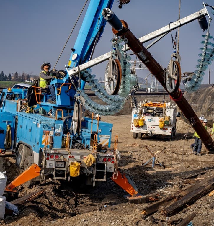 Digger derrick lifting a crossarm with glass insulator strings