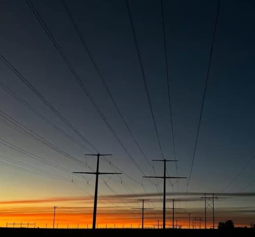 Transmission lines silhouetted against a sunset