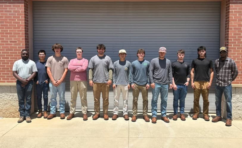 Class of young lineworkers lined up outside a training shop